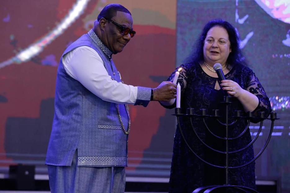 H. E. Shlomit Sufa Lighting Hanukkah Candle with Archbishop Duncan Williams (photo credit: MFA Accra) H. E. Shlomit Sufa Lighting Hanukkah Candle with Archbishop Duncan Williams